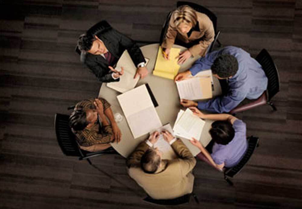 A diverse team of professional trial technology consultants and legal experts collaborating on document review and litigation strategy during a trial preparation meeting.